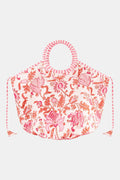 The Amanda Bondi Bag by Roller Rabbit is a large white canvas bag with circular handles, pink and red floral pattern, and pink-and-white striped trim—ideal for travel or beach outings.