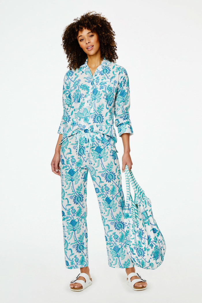 The Amanda Bondi Bag by Roller Rabbit is an oversized canvas bag with circular handles and side ties, showcasing a blue and green floral pattern on white plus blue-and-white striped accents—perfect for travel.