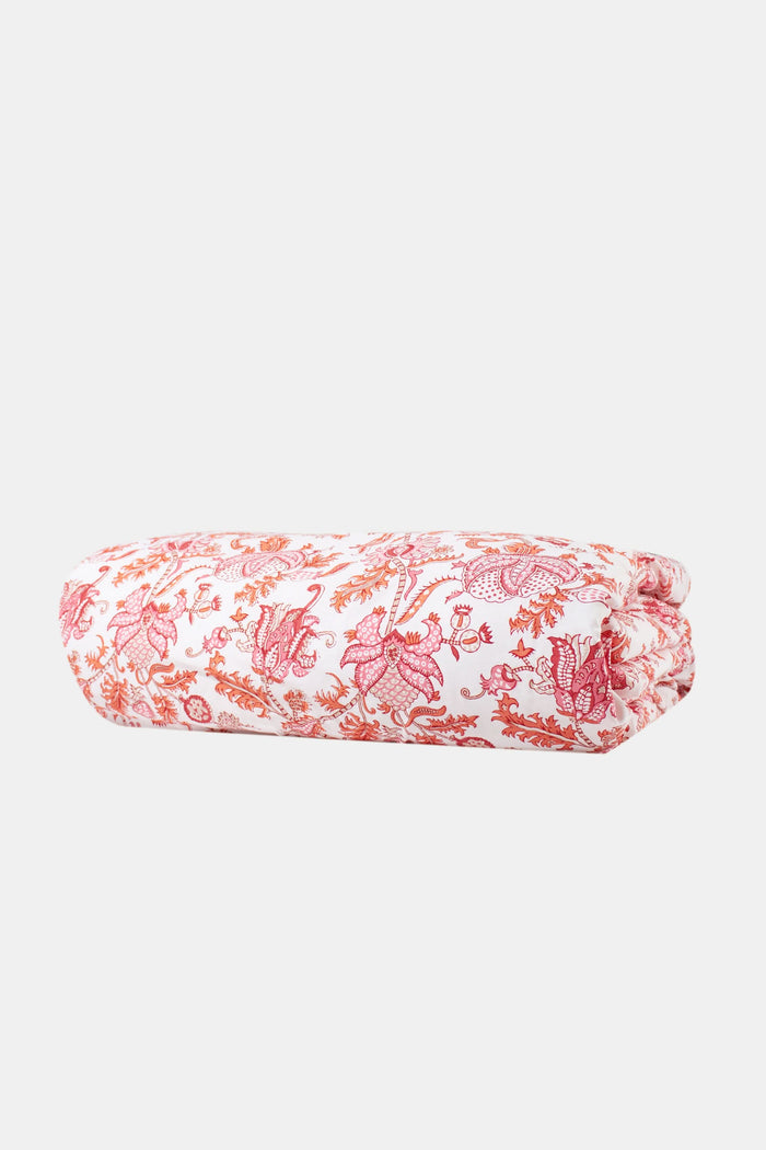A bed featuring the Roller Rabbit Amanda Duvet Cover, a 300 thread count cotton piece in vibrant pink and orange botanical print, shown with a white carved headboard and white curtains in the background.