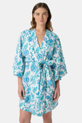 A woman models the Roller Rabbit Amanda Kimono, a knee-length, light blue and white floral cambric cotton robe with wide sleeves and a matching belt, standing against a plain white background.