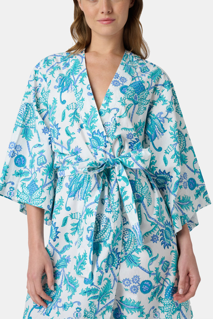 A woman models the Roller Rabbit Amanda Kimono, a knee-length, light blue and white floral cambric cotton robe with wide sleeves and a matching belt, standing against a plain white background.