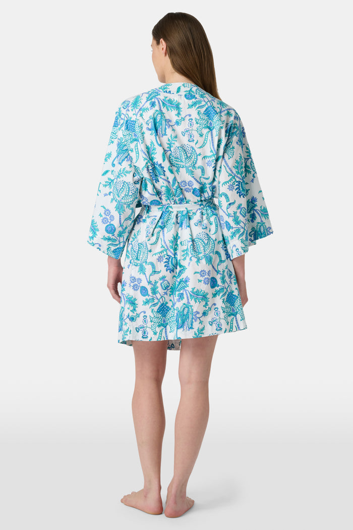 A woman models the Roller Rabbit Amanda Kimono, a knee-length, light blue and white floral cambric cotton robe with wide sleeves and a matching belt, standing against a plain white background.