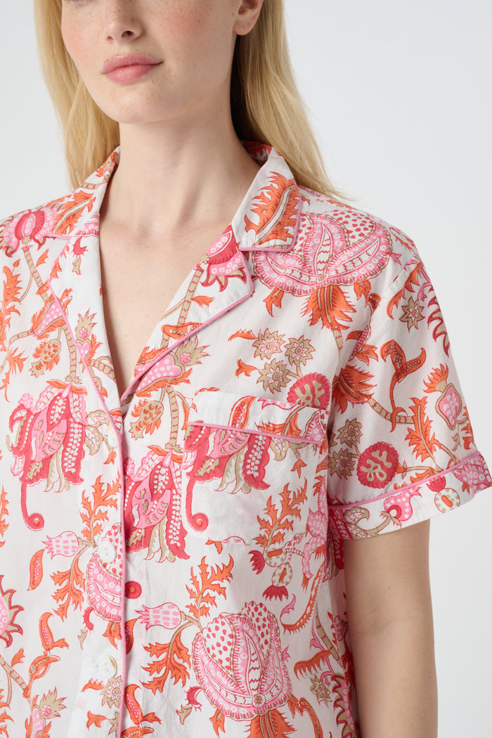 A woman poses against a plain background in the Roller Rabbit Amanda Lulu Set—cotton, short-sleeve, button-up pajamas with matching shorts in a pink and orange floral print.