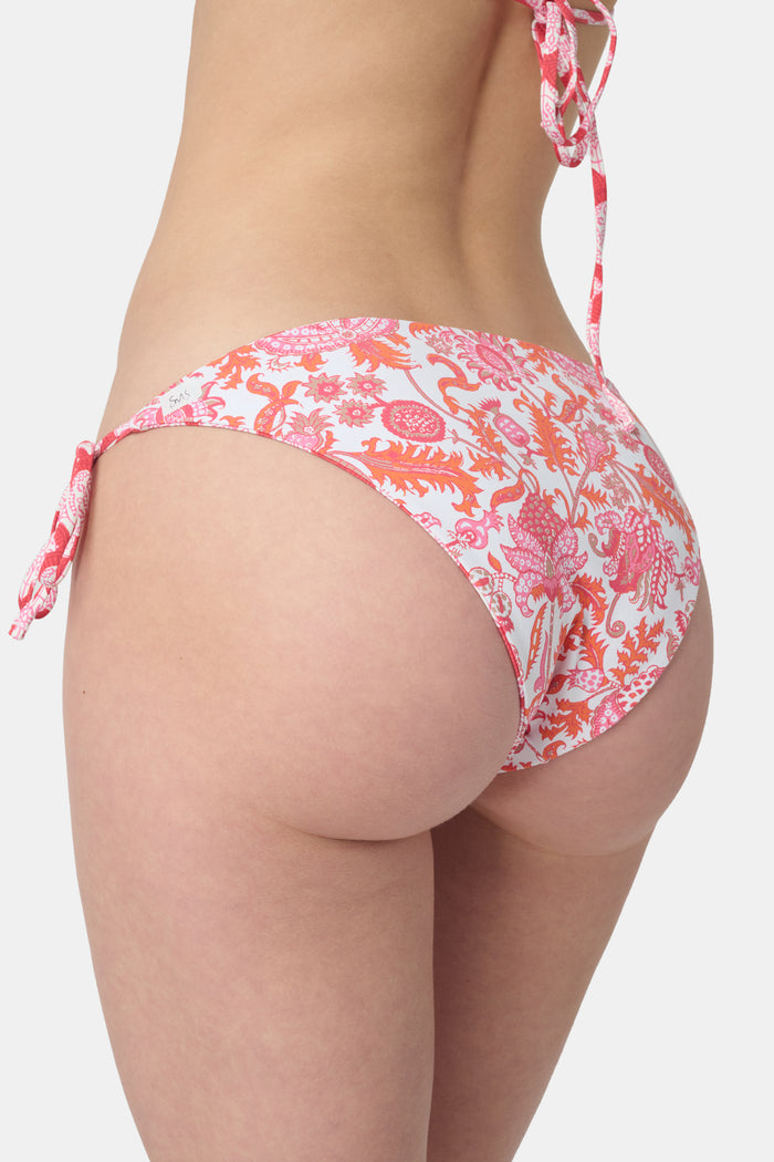 A person wears the Roller Rabbit Amanda/Jemina Serena Bikini Bottom, featuring UPF 50+ protection, white heart-shaped patterns, and side tie strings, shown from waist to mid-thigh against a plain background.