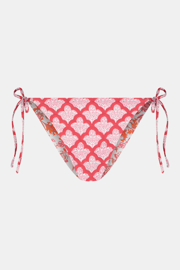 A person wears the Roller Rabbit Amanda/Jemina Serena Bikini Bottom, featuring UPF 50+ protection, white heart-shaped patterns, and side tie strings, shown from waist to mid-thigh against a plain background.