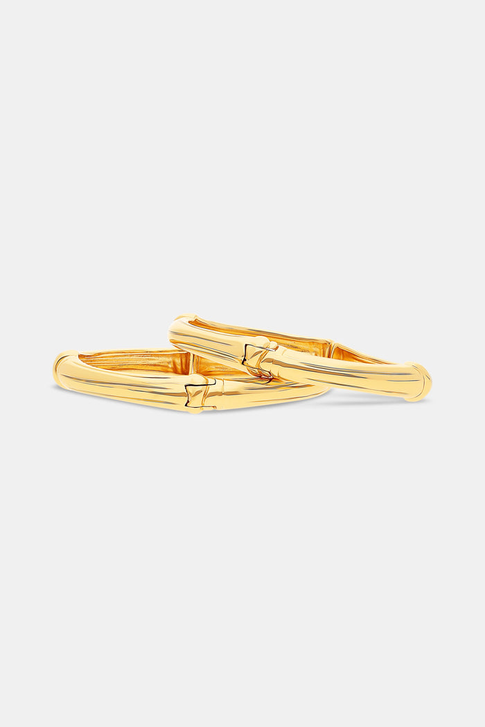 A close-up of a person’s hand wearing the Roller Rabbit Bamboo Bangle Set, resting against a dress with a bold geometric red, orange, and white pattern.