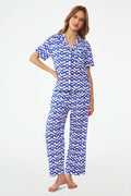 A woman stands barefoot in the Roller Rabbit Big Cata Liza Set, a matching short-sleeve pajama set made from cambric cotton with a blue and white Big Cata print, posing against a plain white background.
