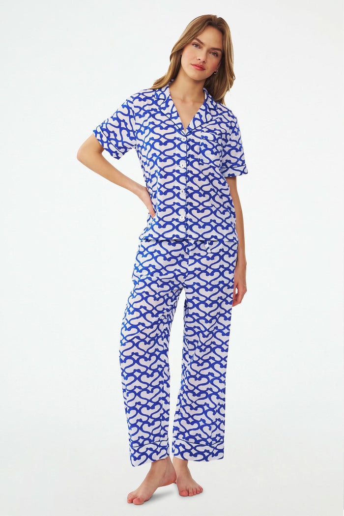 A woman stands barefoot in the Roller Rabbit Big Cata Liza Set, a matching short-sleeve pajama set made from cambric cotton with a blue and white Big Cata print, posing against a plain white background.