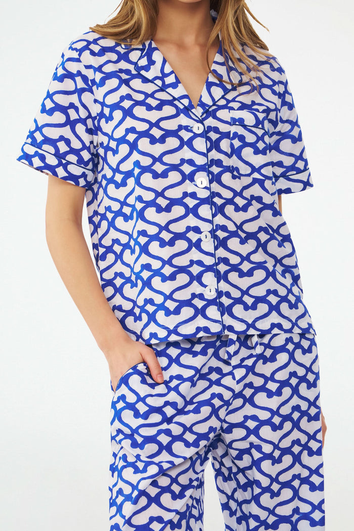 A woman stands barefoot in the Roller Rabbit Big Cata Liza Set, a matching short-sleeve pajama set made from cambric cotton with a blue and white Big Cata print, posing against a plain white background.