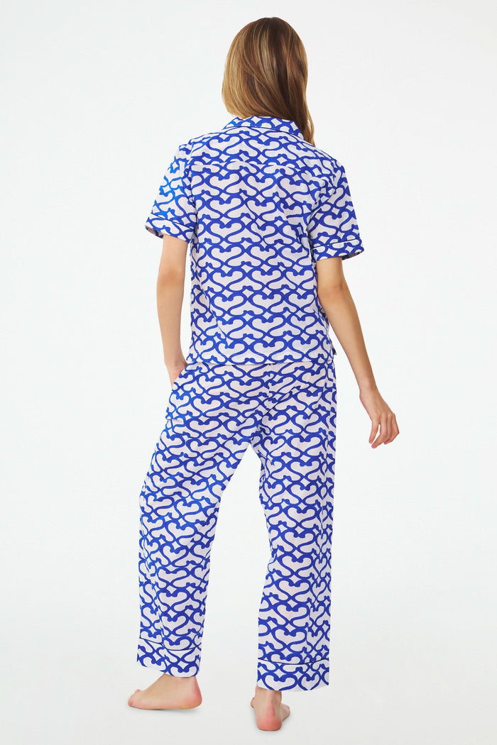A woman stands barefoot in the Roller Rabbit Big Cata Liza Set, a matching short-sleeve pajama set made from cambric cotton with a blue and white Big Cata print, posing against a plain white background.