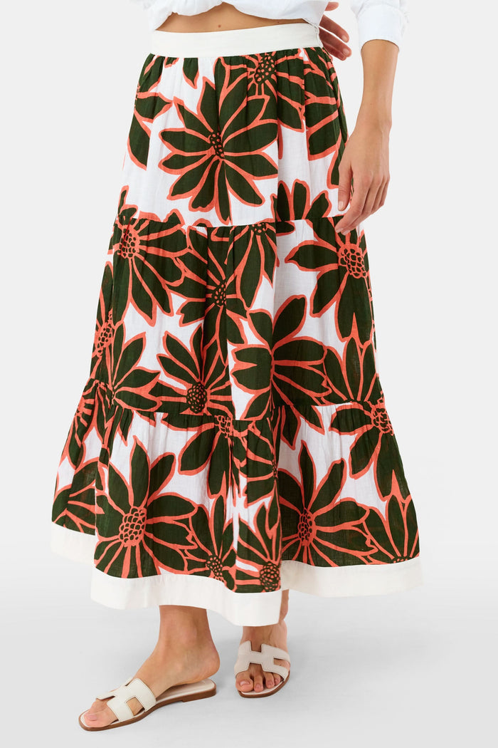 A person wears a white Roller Rabbit Blooming Daisies Carlisa Skirt with bold black and orange floral prints, paired with a white top and white sandals.