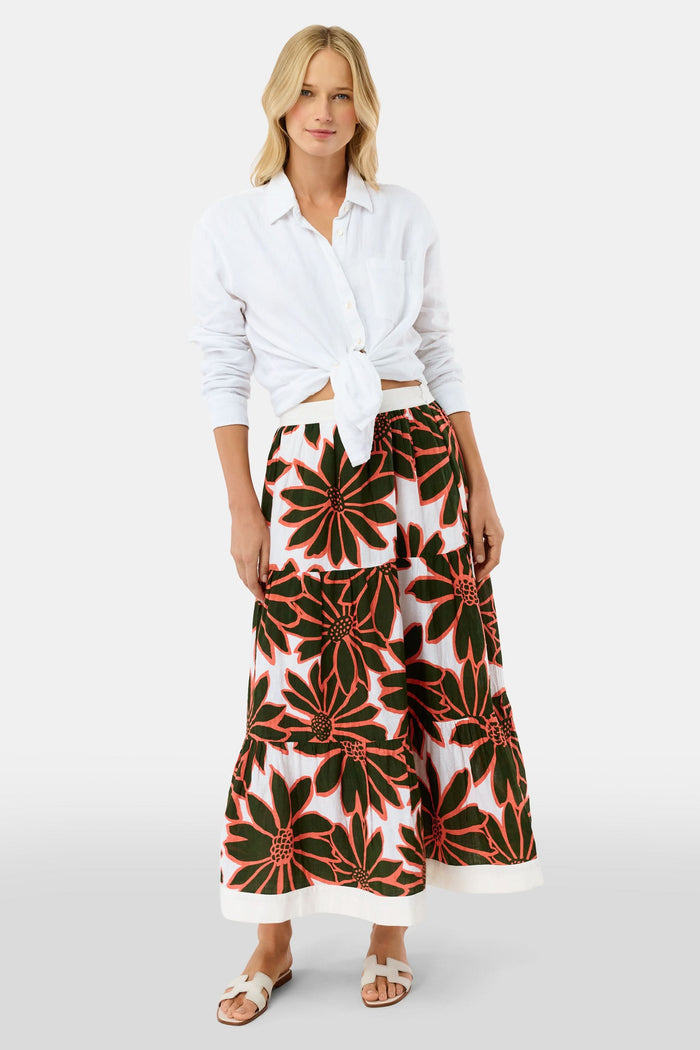 A person wears a white Roller Rabbit Blooming Daisies Carlisa Skirt with bold black and orange floral prints, paired with a white top and white sandals.