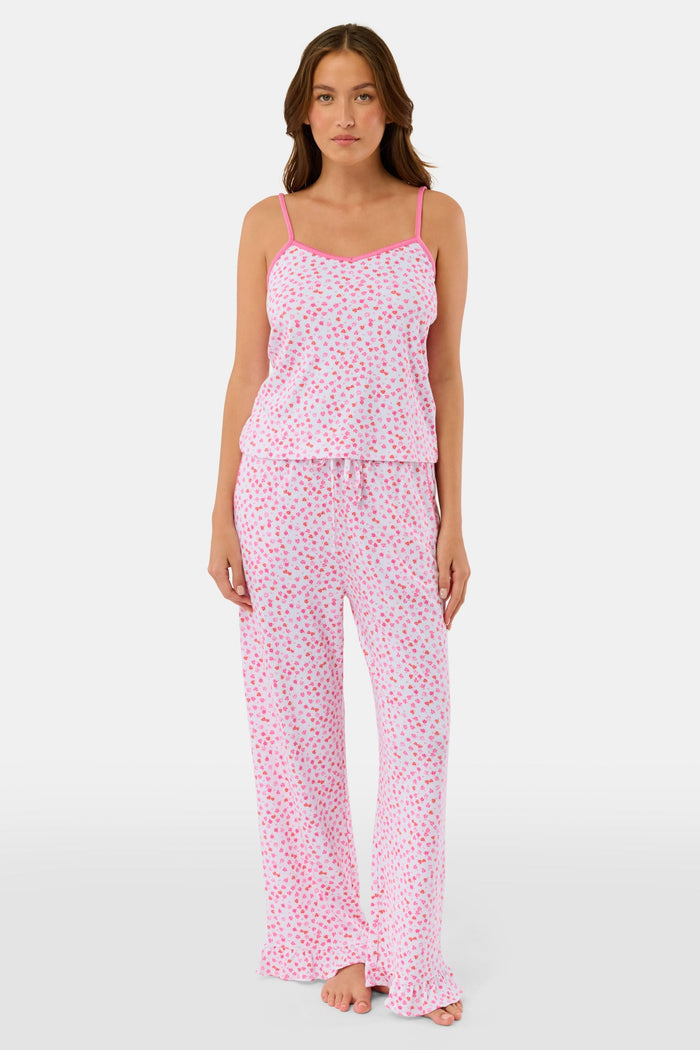 A woman faces forward, barefoot against a plain white background, wearing the Roller Rabbit Bouquet Lily Set—a pink and white polka dot pajama with a sleeveless top and long pants made from soft Pima Soft fabric.
