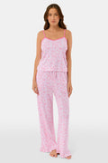 A woman faces forward, barefoot against a plain white background, wearing the Roller Rabbit Bouquet Lily Set—a pink and white polka dot pajama with a sleeveless top and long pants made from soft Pima Soft fabric.