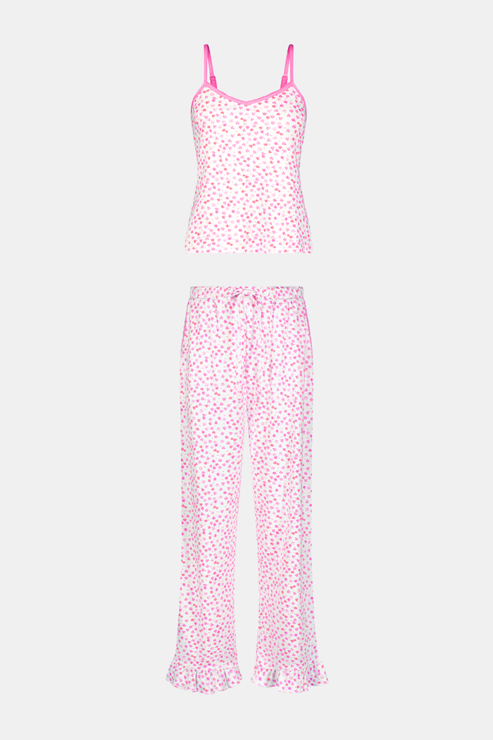 A woman faces forward, barefoot against a plain white background, wearing the Roller Rabbit Bouquet Lily Set—a pink and white polka dot pajama with a sleeveless top and long pants made from soft Pima Soft fabric.