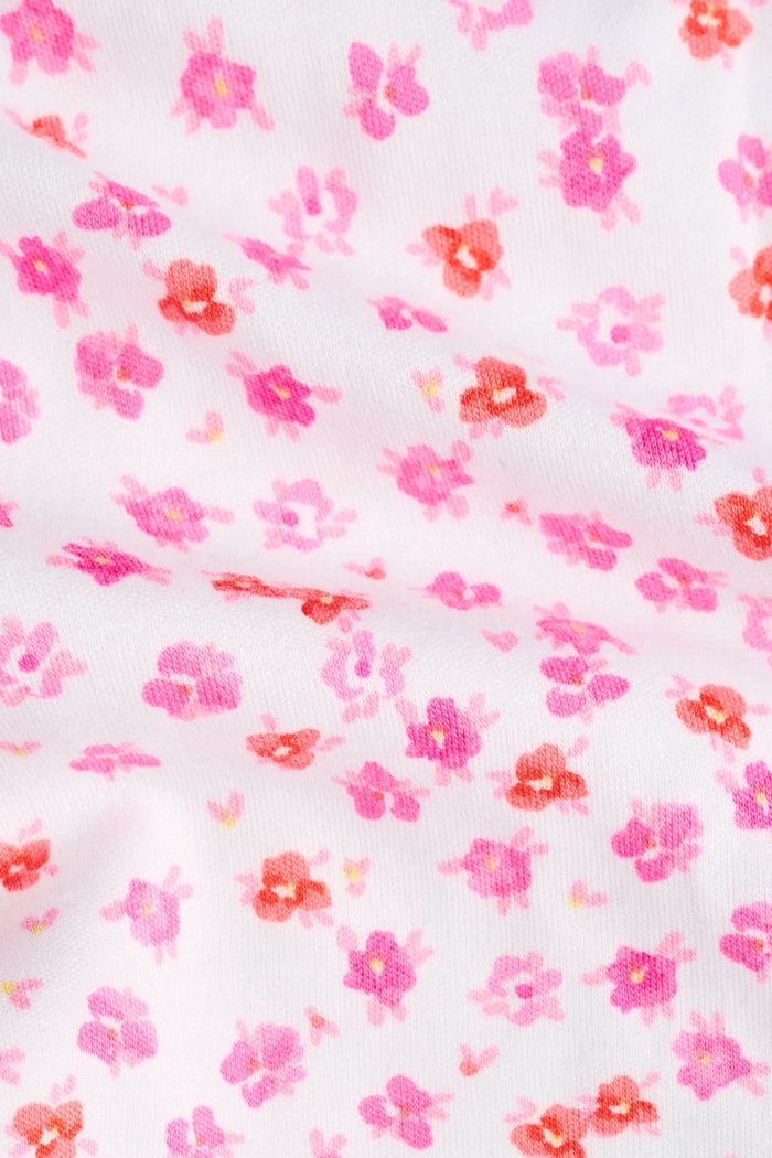 A woman faces forward, barefoot against a plain white background, wearing the Roller Rabbit Bouquet Lily Set—a pink and white polka dot pajama with a sleeveless top and long pants made from soft Pima Soft fabric.