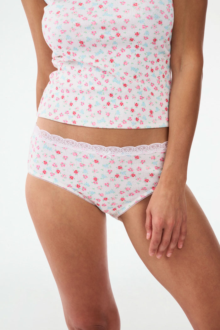 A person models the Roller Rabbit Bouquet Pointelle Cornelia Hipster and a matching floral tank top, both featuring scalloped lace trim, against a plain light background. The focus is from shoulders to upper thighs.