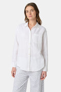 A woman wears the Roller Rabbit Boyfriend Shirt, a menswear-inspired white button-up with a chest pocket, paired with loose white pants featuring a navy polka dot pattern, standing against a plain light background.