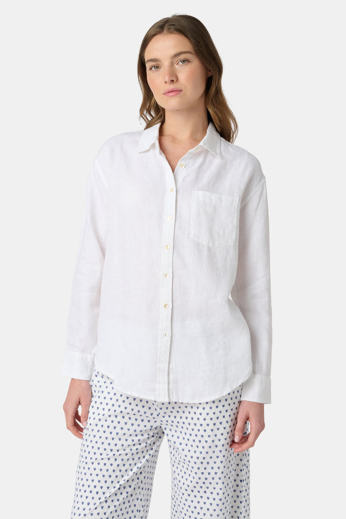 A woman wears the Roller Rabbit Boyfriend Shirt, a menswear-inspired white button-up with a chest pocket, paired with loose white pants featuring a navy polka dot pattern, standing against a plain light background.