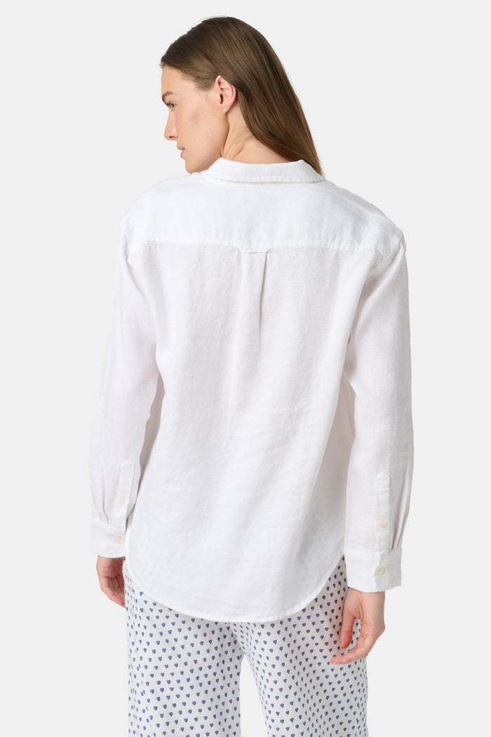 A woman wears the Roller Rabbit Boyfriend Shirt, a menswear-inspired white button-up with a chest pocket, paired with loose white pants featuring a navy polka dot pattern, standing against a plain light background.