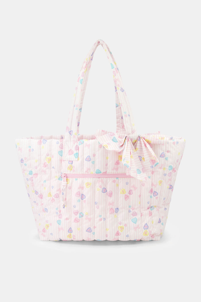 The Roller Rabbit Candy Heart Stripe Quilted Tote is a pastel pink weekend bag with scalloped edges, a matching bow on one handle, double handles, and a front zipper pocket.