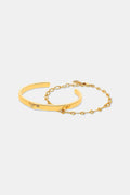 The Roller Rabbit Citra Fish Bracelet Set features a solid open cuff with an engraved detail and a delicate round-link chain with clasp, both shown on white. This elegant gold set is versatile for any occasion.