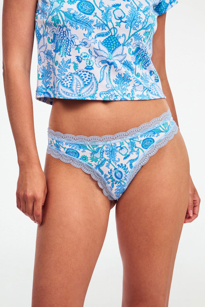 The Roller Rabbit Classic Core Thong 4 Pack features four pairs of lace-trim women’s underwear in pastel shades—pink with hearts, blue with flowers, printed blue, and green—offering soft cotton comfort and cute style.