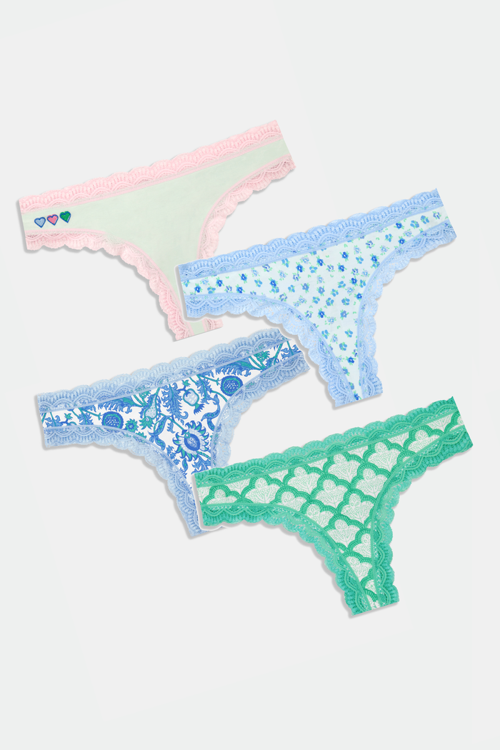 The Roller Rabbit Classic Core Thong 4 Pack features four pairs of lace-trim women’s underwear in pastel shades—pink with hearts, blue with flowers, printed blue, and green—offering soft cotton comfort and cute style.