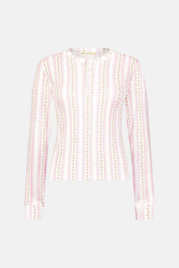 A woman wears the Roller Rabbit Daisy Heart Stripe Rosemary Top with pink, green, and white stripes, featuring a long-sleeved henley design, against a plain light background.