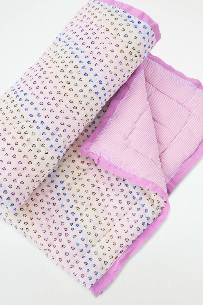 The Roller Rabbit Disco Hearts Baby Quilt, made from 100 cotton, features a white base with multicolored hearts, a pink striped reverse, and light purple trim. It's folded and displayed on a white surface.