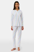 A woman stands barefoot in Roller Rabbit’s Disco Hearts Pajamas, featuring a long-sleeved, buttoned top and straight-leg pants with colorful polka dots on white for comfort and style.