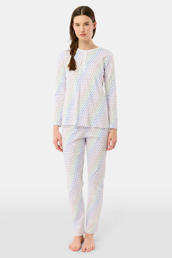 A woman stands barefoot in Roller Rabbit’s Disco Hearts Pajamas, featuring a long-sleeved, buttoned top and straight-leg pants with colorful polka dots on white for comfort and style.