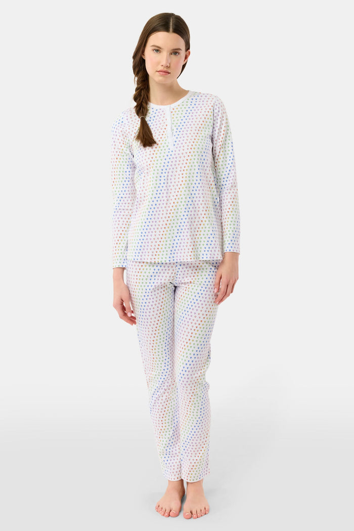 A woman stands barefoot in Roller Rabbit’s Disco Hearts Pajamas, featuring a long-sleeved, buttoned top and straight-leg pants with colorful polka dots on white for comfort and style.