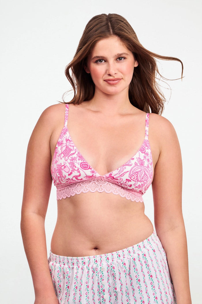 A woman with medium-length dark hair models the Ditsy Amanda Mercer Bralette by Roller Rabbit, featuring lace trim and a floral pattern, standing against a plain light background.