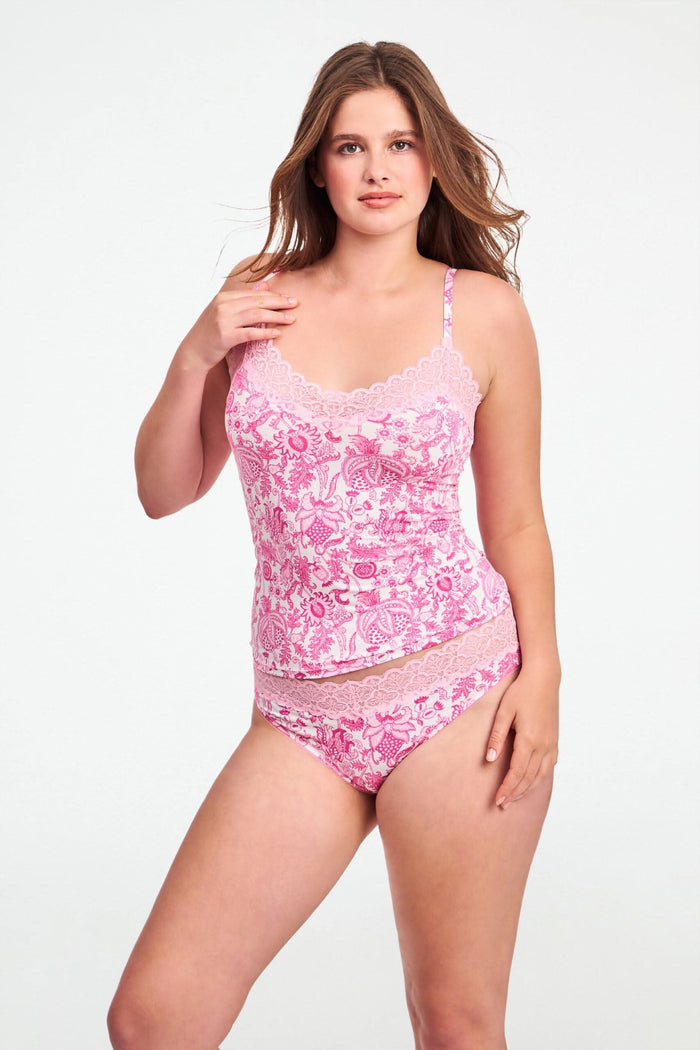 A woman with long brown hair poses confidently against a plain light background, wearing the Roller Rabbit Ditsy Amanda Perry Cami—a matching camisole and underwear set with pink and white floral lace and delicate scalloped trim.