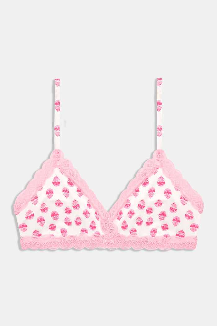 A woman wears a Roller Rabbit Ditsy Daisy Pointelle Jane Bralette—a light pink floral print bra with lace trim—standing against a plain background.