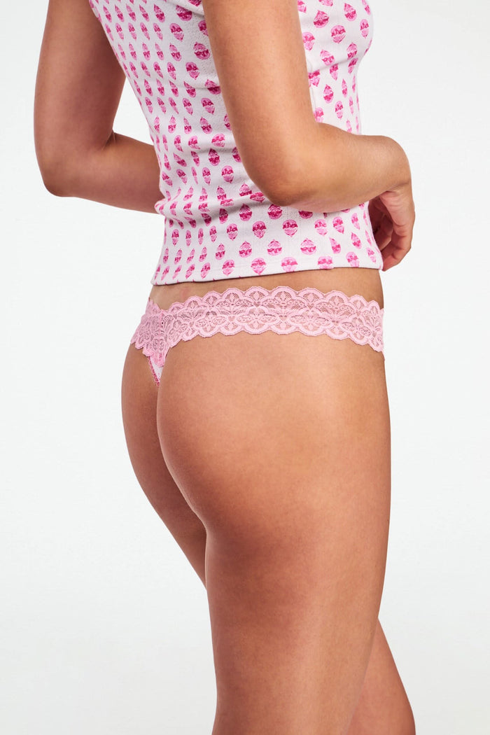 A person models the Roller Rabbit Ditsy Daisy Pointelle Jay Thong and a white tank top with pink cupcake patterns, standing against a plain white background. Only their torso and upper legs are visible.