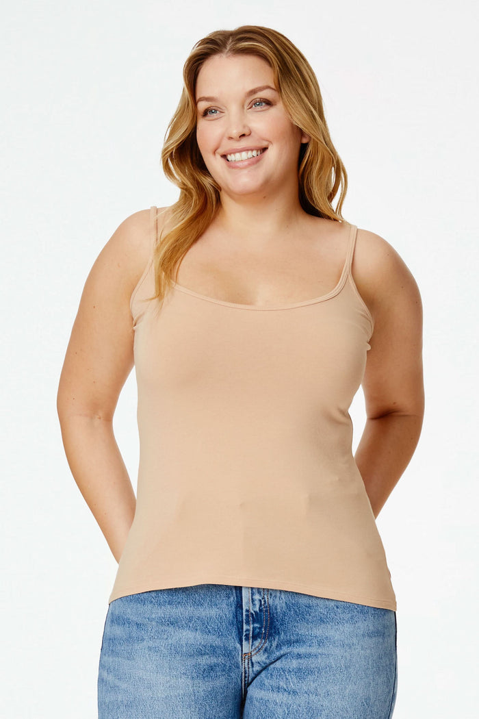 A smiling woman with curly hair wears the Roller Rabbit Dream Camisole in beige and light blue denim shorts, posing with one hand on her hip against a plain white background.