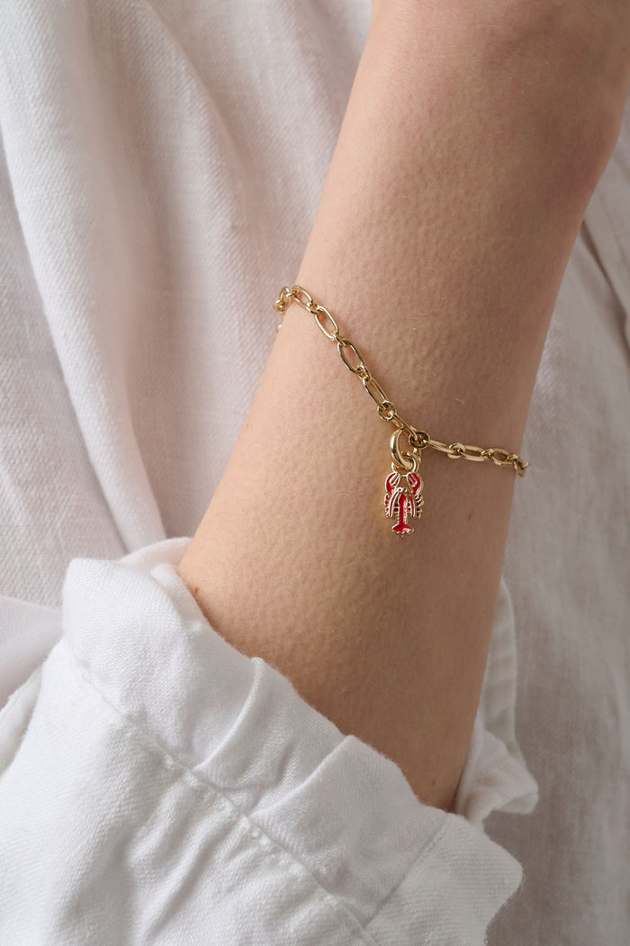 The Roller Rabbit Enamel Lobster Charm, a gold pendant with red enamel details, is shown against a plain light gray background.