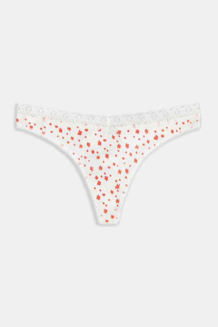 A person wears a white tank top and the Roller Rabbit Étoiles Pointelle Banks Thong, featuring soft cotton with small red floral prints and lace trim, shown from mid-torso to upper thigh for a panty line-free look.