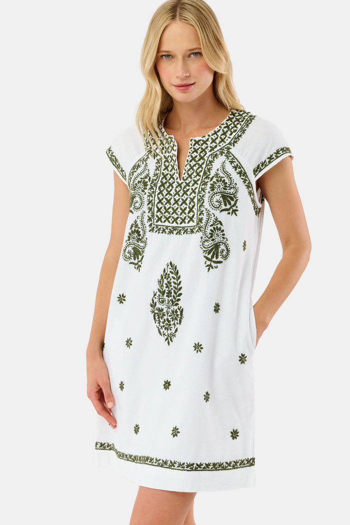 A woman in the Roller Rabbit Faith Dress—a 100 cotton midi with green floral and geometric embroidery—stands with one hand in her pocket against a plain light background.