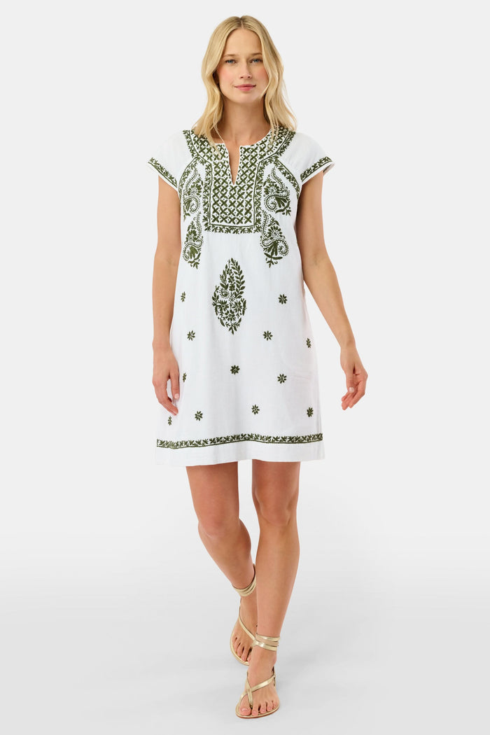 A woman in the Roller Rabbit Faith Dress—a 100 cotton midi with green floral and geometric embroidery—stands with one hand in her pocket against a plain light background.