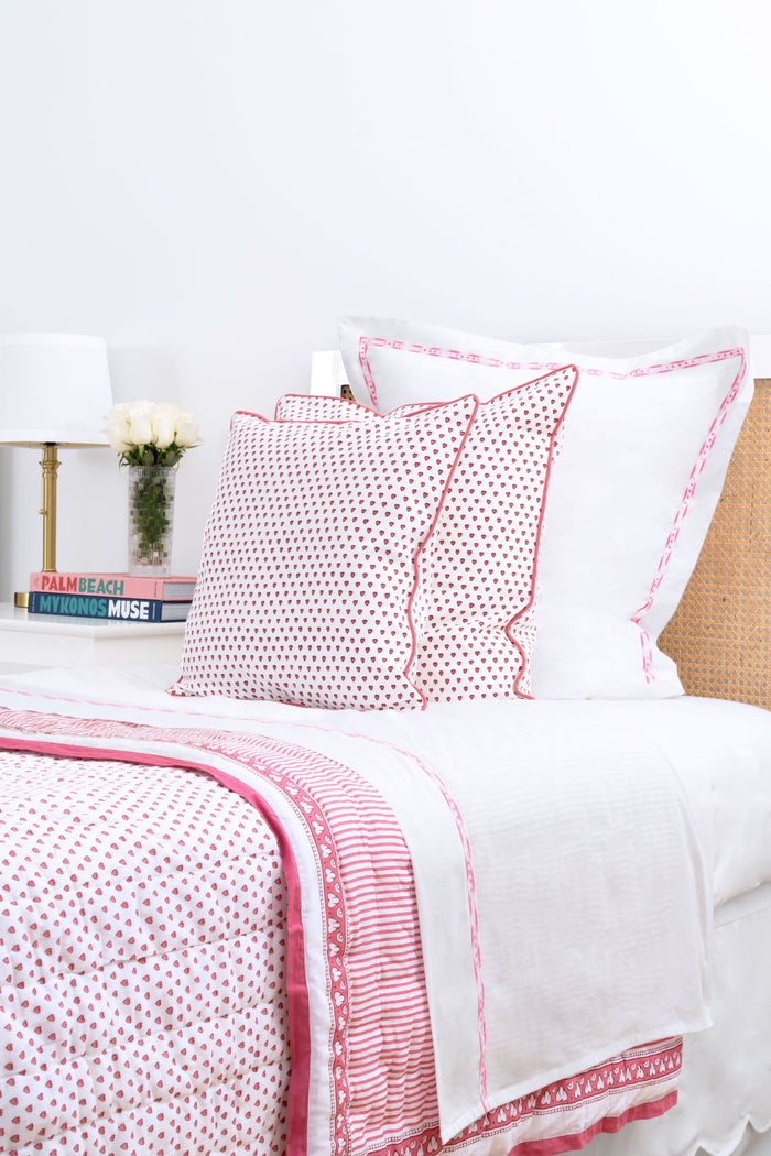 Two white Francis Embroidered Pillowcases by Roller Rabbit, made of 100 cotton with a 300 thread count, are arranged on a matching bed. A scalloped, floral headboard provides an elegant backdrop.