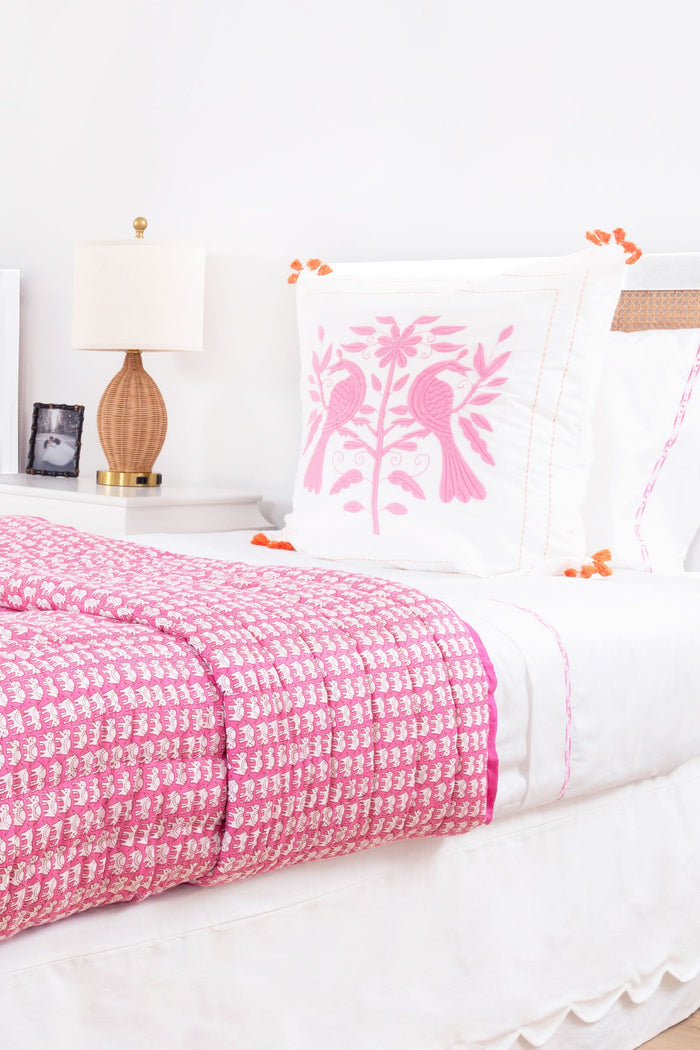 The Francis Embroidered Sheet Set by Roller Rabbit features white cotton sheets and pillowcases with a thin pink border, perfectly complementing an ornate white patterned headboard for a clean, elegant look.