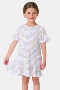 A young child smiles in the Roller Rabbit Girls Disco Hearts Esme Dress, a short-sleeve cotton dress with a ruffled hem and colorful heart patterns, set against a plain, light background.