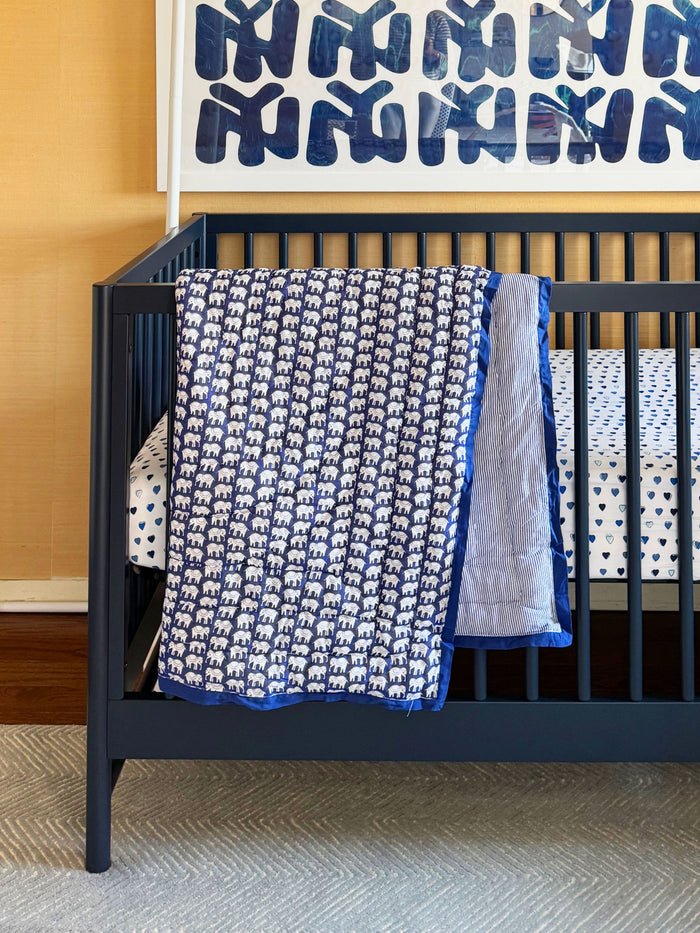 The Roller Rabbit Hathi Baby Quilt features a blue background with a white elephant print, blue and white striped lining, and a solid blue border, all crafted from soft cotton for comfort.