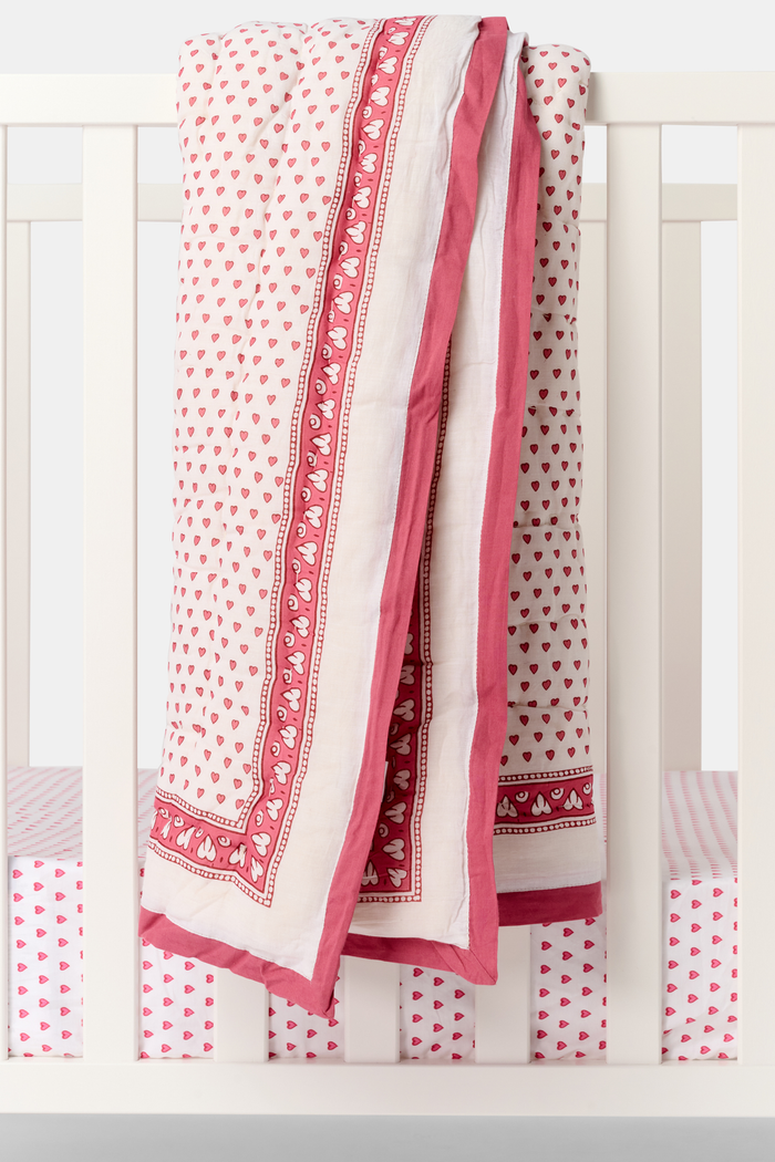 The Roller Rabbit Hearts Baby Quilt features a white cotton background with small red hearts print and a red and white border adorned with geometric and floral designs.