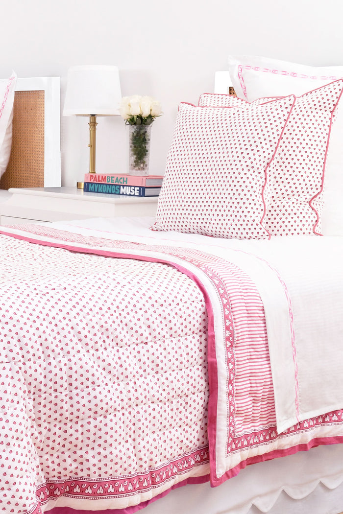 The Roller Rabbit Hearts Decorative Pillow is a rectangular white pillow with an evenly spaced pink heart print and red piping, crafted from 100 cotton for comfort and softness.