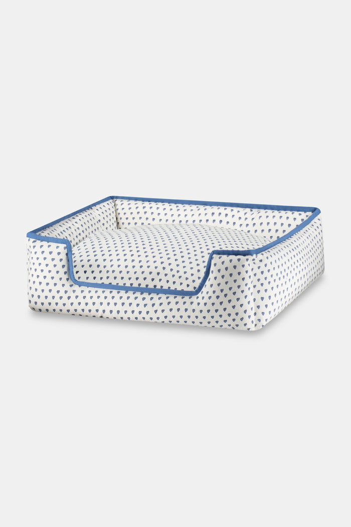 The Roller Rabbit Hearts Dog Bed features a plush rectangular design with blue trim, a lowered front edge, and an all-over blue heart pattern. This machine washable dog bed combines comfort and style for your pet.