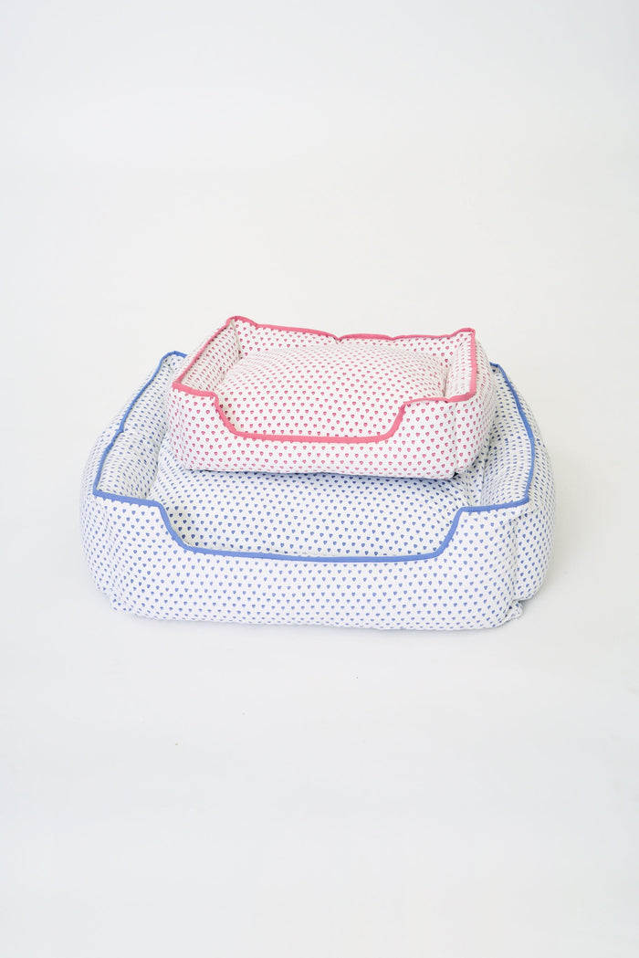 The Roller Rabbit Hearts Dog Bed features a plush rectangular design with blue trim, a lowered front edge, and an all-over blue heart pattern. This machine washable dog bed combines comfort and style for your pet.